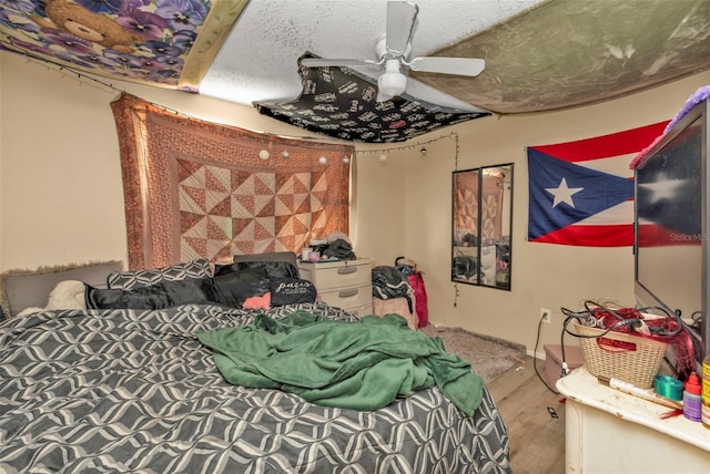 bedroom featuring ceiling fan, a textured ceiling, and wood finished floors