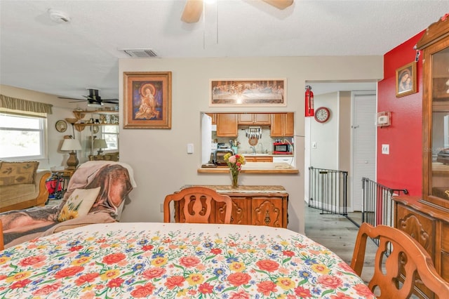 bedroom featuring visible vents, ceiling fan, wood finished floors, a textured ceiling, and a sink