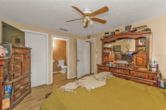 bedroom featuring a ceiling fan, light wood-type flooring, visible vents, and a textured ceiling