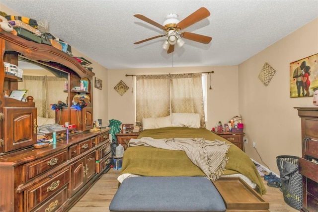 bedroom featuring a textured ceiling, ceiling fan, and light wood-style floors