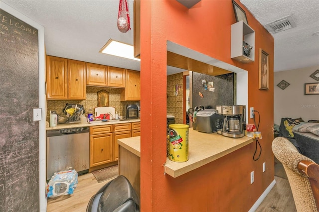 kitchen featuring light wood finished floors, visible vents, decorative backsplash, light countertops, and stainless steel dishwasher