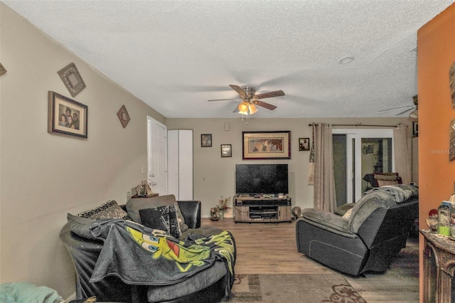 living room featuring a ceiling fan, a textured ceiling, and wood finished floors