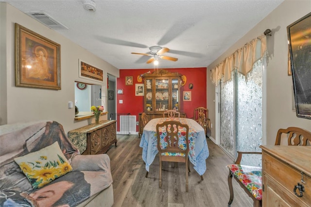 dining space with a textured ceiling, wood finished floors, visible vents, and a ceiling fan