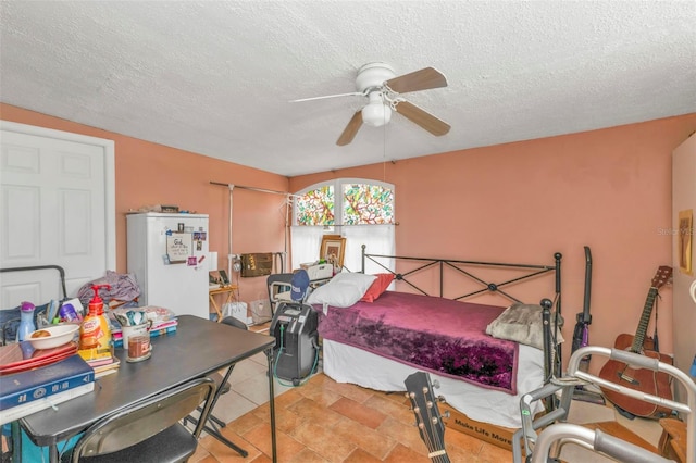 bedroom featuring ceiling fan, a textured ceiling, and freestanding refrigerator