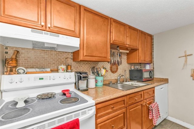 kitchen with light countertops, decorative backsplash, a sink, white appliances, and under cabinet range hood