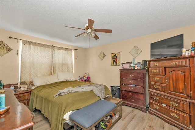 bedroom with ceiling fan, a textured ceiling, and light wood finished floors