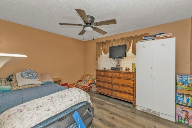 bedroom featuring ceiling fan, a textured ceiling, and wood finished floors