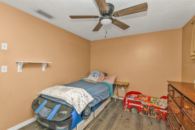 bedroom with a textured ceiling, ceiling fan, dark wood-style flooring, and visible vents