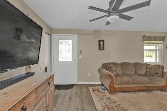 living area featuring ceiling fan, light wood-style flooring, and baseboards