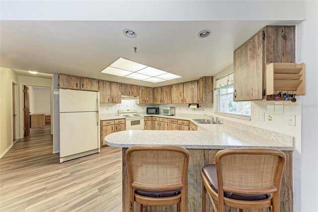 1052 Hinton St, Port Charlotte, FL 33952 - kitchen featuring white appliances, a peninsula, light countertops, and a sink