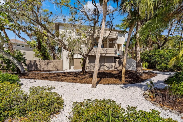 rear view of property with fence and stairway