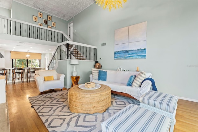 living room featuring visible vents, an ornate ceiling, wood finished floors, stairs, and a high ceiling