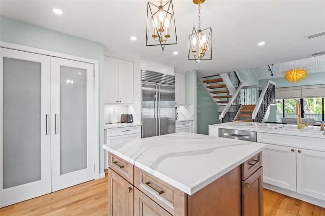 kitchen featuring light wood finished floors, appliances with stainless steel finishes, a kitchen island, and light stone countertops