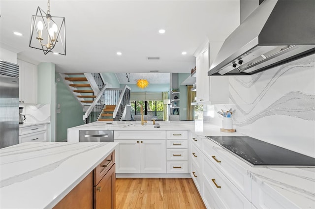 kitchen featuring range hood, decorative backsplash, appliances with stainless steel finishes, light wood-style floors, and white cabinets