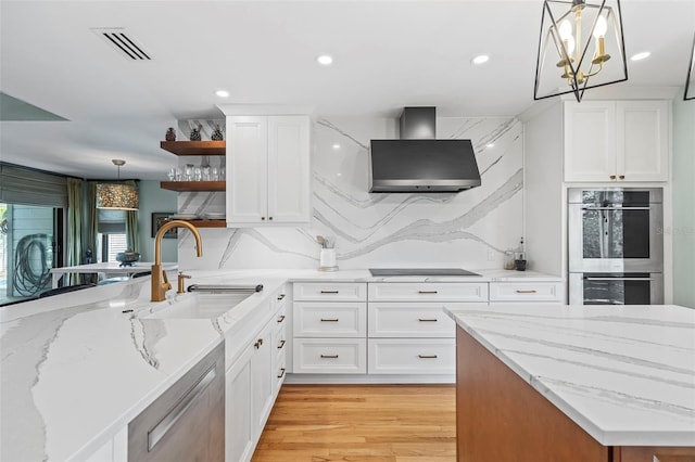 kitchen featuring a sink, visible vents, wall chimney range hood, appliances with stainless steel finishes, and open shelves