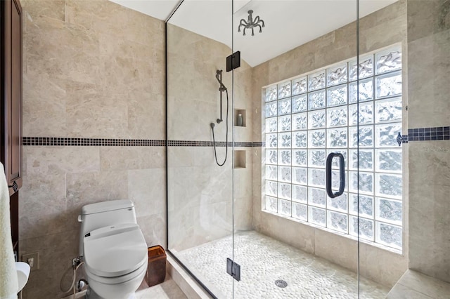 full bath with a stall shower, toilet, and tile walls