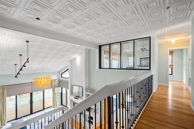 hall with an ornate ceiling, an upstairs landing, baseboards, and wood finished floors