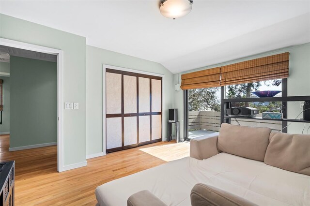 bedroom with baseboards, vaulted ceiling, and wood finished floors