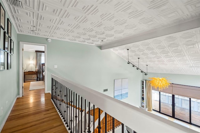 hallway with lofted ceiling with beams, wood finished floors, an ornate ceiling, and baseboards