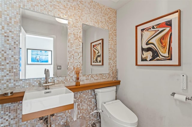 bathroom featuring a sink, toilet, and decorative backsplash