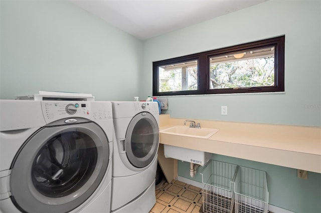 clothes washing area featuring a sink, laundry area, and washer and dryer