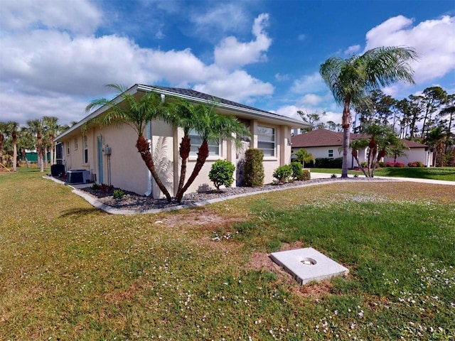 view of front of home featuring a front yard, central air condition unit, and stucco siding