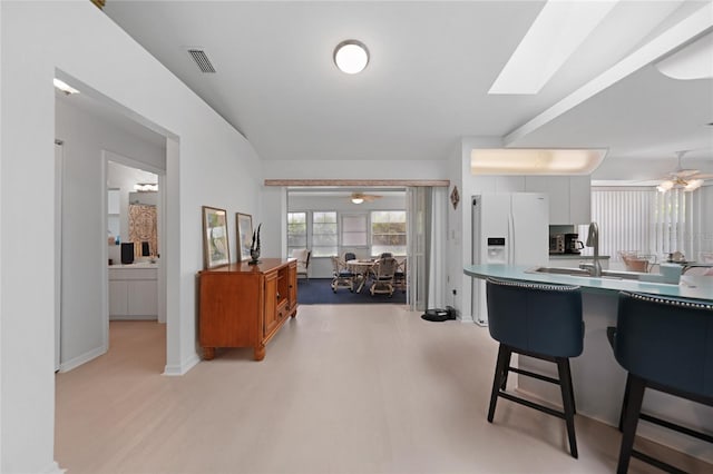 kitchen with a ceiling fan, light wood-style flooring, visible vents, and a breakfast bar area