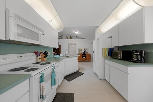 kitchen with white appliances, a sink, white cabinetry, vaulted ceiling, and light countertops