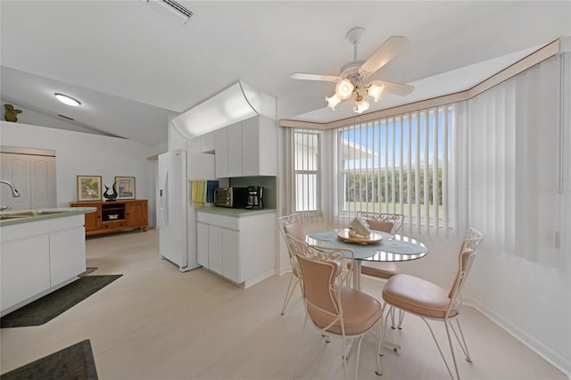 dining room featuring lofted ceiling, light wood-style flooring, visible vents, and a ceiling fan