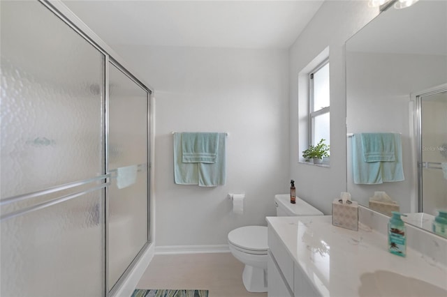 bathroom with a stall shower, vanity, toilet, and baseboards