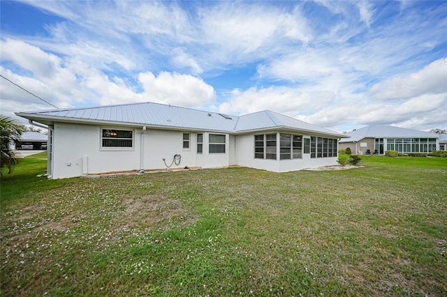 back of house featuring metal roof, a lawn, and a sunroom