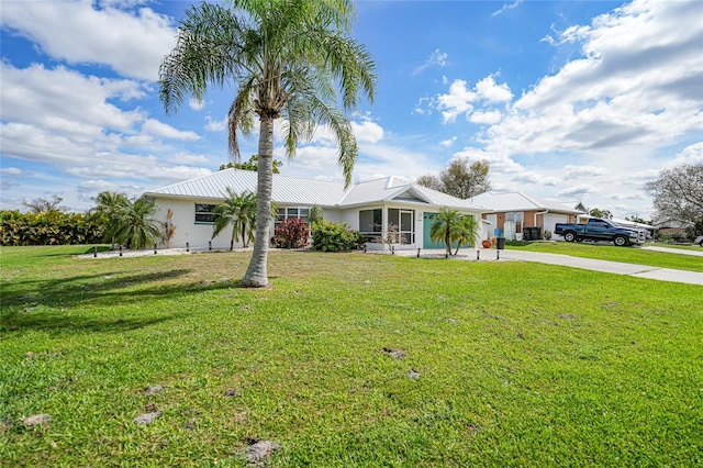 ranch-style house featuring metal roof, driveway, and a front lawn