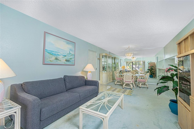 carpeted living area featuring a notable chandelier and a textured ceiling