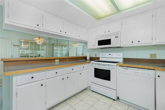 kitchen with dark countertops, white appliances, white cabinets, and light tile patterned flooring