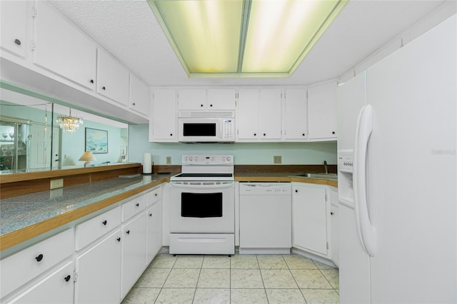 kitchen featuring light tile patterned floors, white appliances, a sink, and white cabinetry