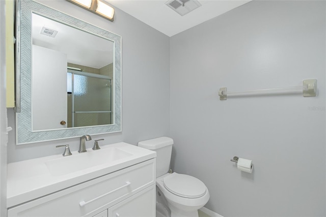 bathroom featuring toilet, a shower with shower door, visible vents, and vanity