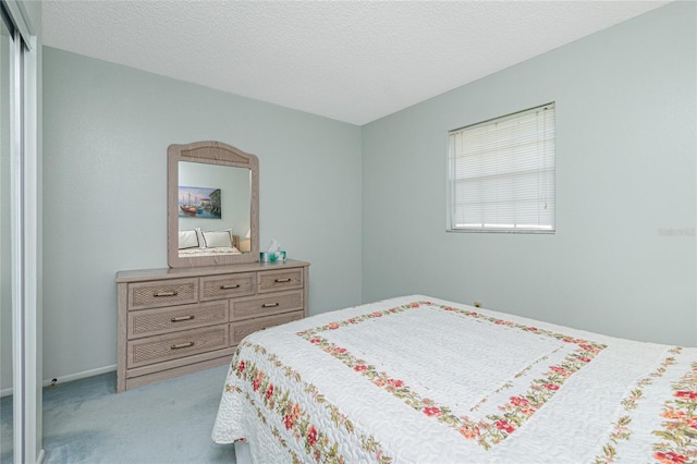 bedroom with a closet, a textured ceiling, and light colored carpet