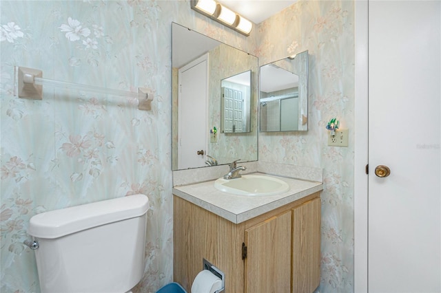 bathroom with vanity, toilet, and wallpapered walls