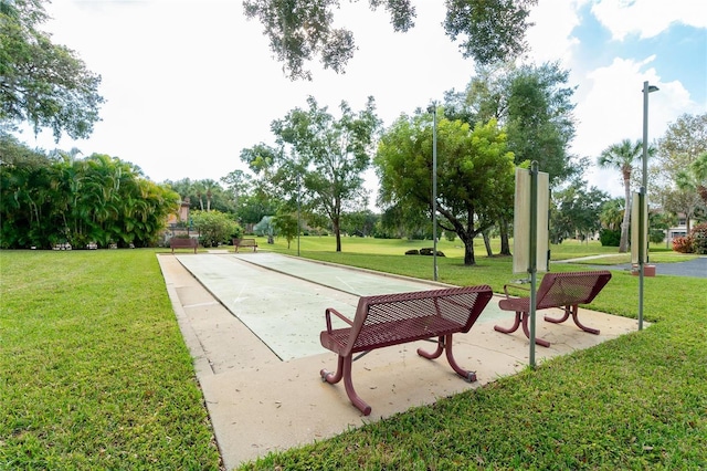 view of property's community with shuffleboard and a yard