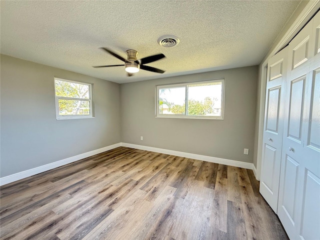 unfurnished bedroom featuring visible vents, baseboards, a textured ceiling, and multiple windows