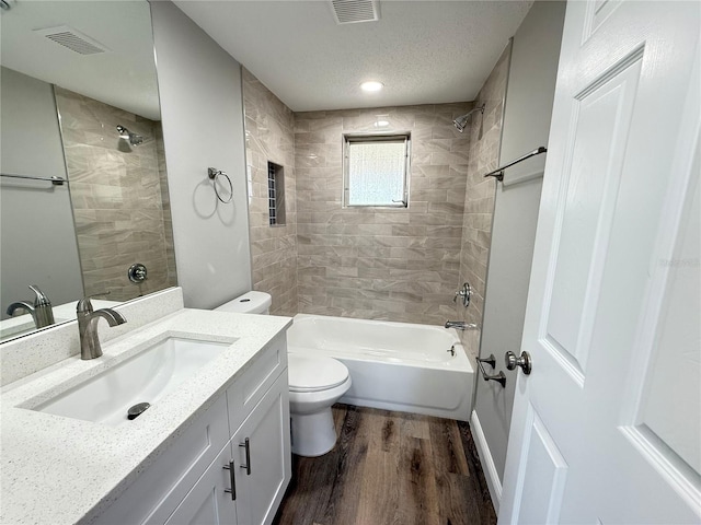 bathroom with wood finished floors, visible vents, shower / bath combination, toilet, and vanity