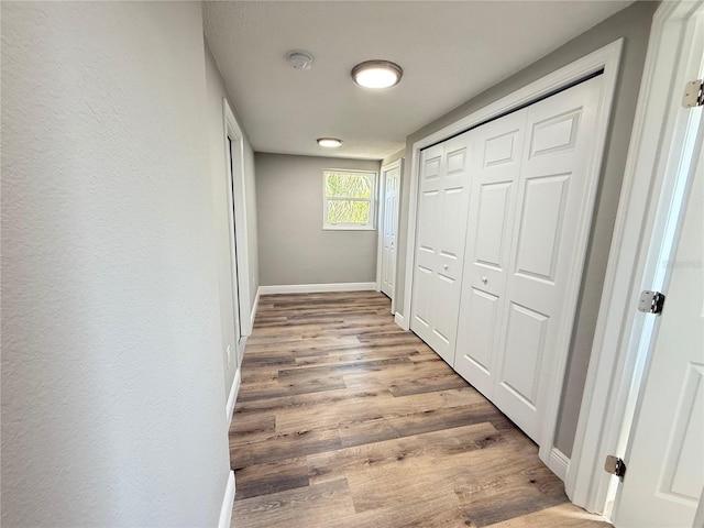 hallway featuring baseboards and wood finished floors