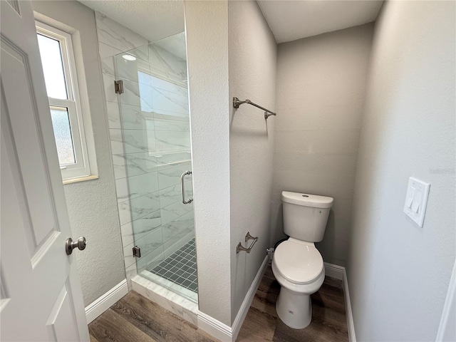 bathroom featuring a shower stall, wood finished floors, toilet, and baseboards