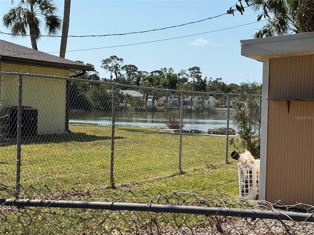 view of yard with central air condition unit, fence, and a water view