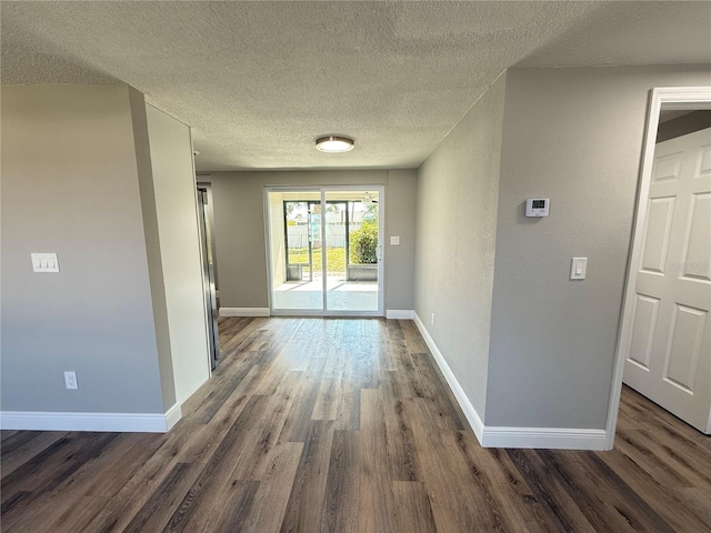 hallway with baseboards, a textured ceiling, and dark wood-style floors