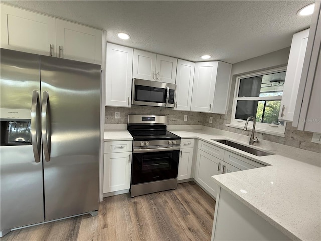 kitchen featuring white cabinets, tasteful backsplash, stainless steel appliances, and a sink
