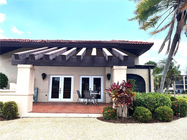 back of house featuring stucco siding and french doors