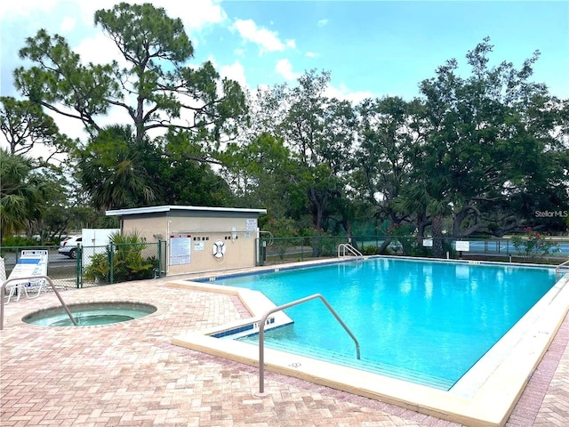 pool with a community hot tub, a patio, and fence