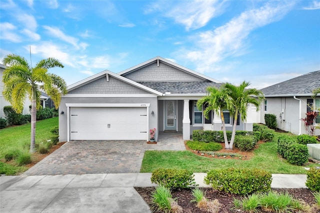 view of front of house featuring decorative driveway, roof with shingles, stucco siding, a garage, and a front lawn