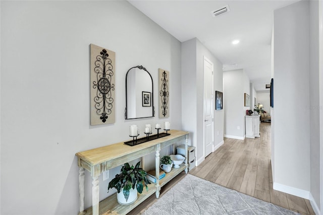 hallway with visible vents, baseboards, wood finished floors, and recessed lighting